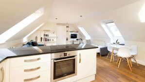 A modern kitchen with a built-in oven and a dining area with a white table and chairs. - Modern Apartment close to Dean Village (Edinburgh)