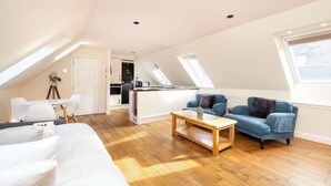A modern loft apartment with a large bed, a blue sofa, a wooden coffee table, and a kitchenette in the background. - Modern Apartment close to Dean Village (Edinburgh)