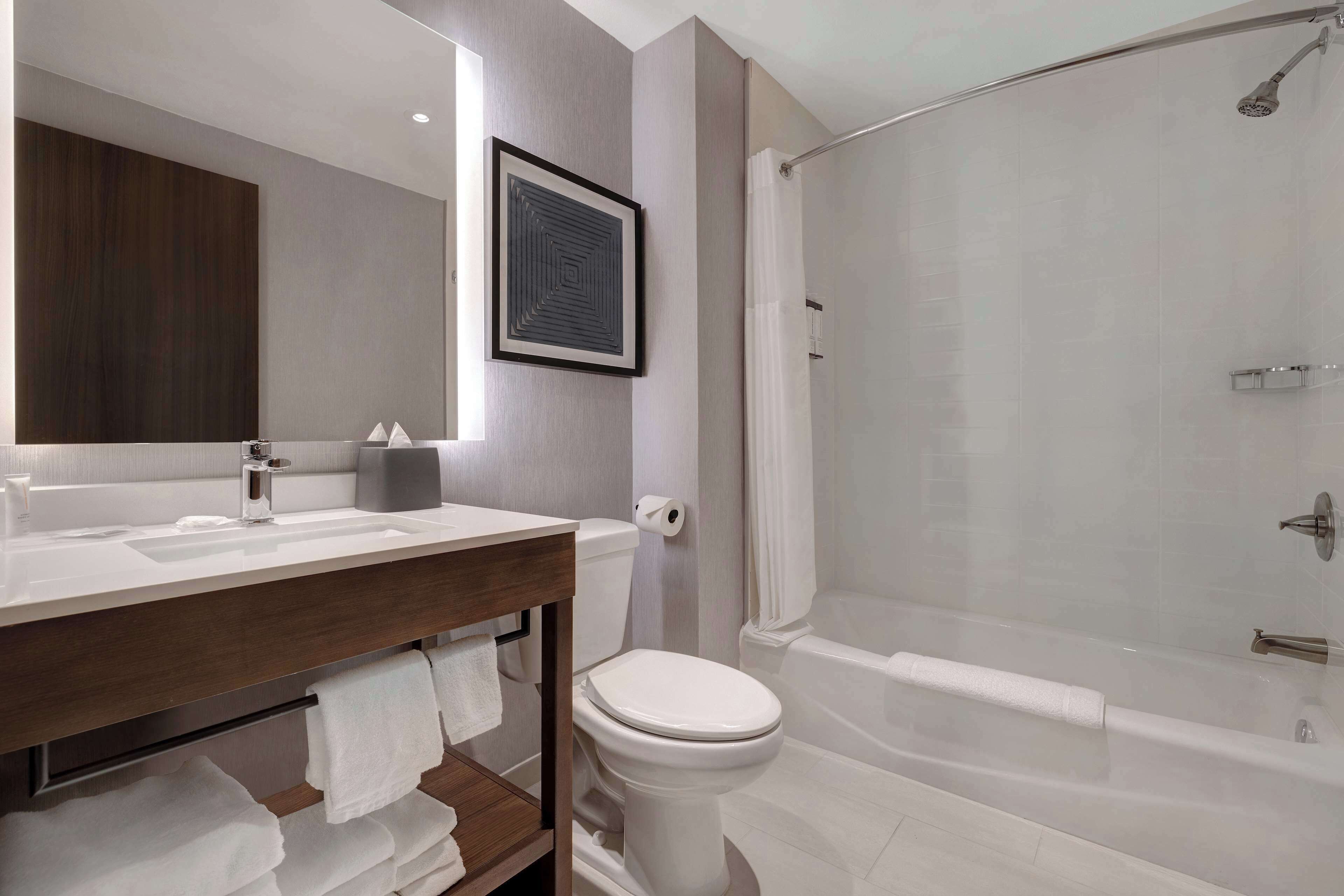 Un baño moderno con un lavamanos, inodoro y bañera blancos.