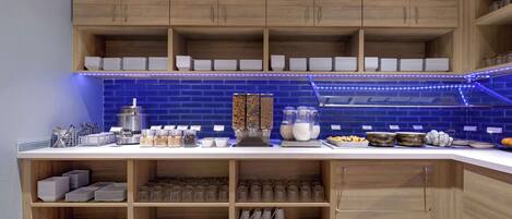 Una cocina con armarios de madera, un respuesto de azulejos azules y estantes llenos de vajilla y utensilios.