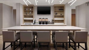 A modern conference room with a long table, six chairs, a flat-screen TV, and shelves with various items. - Hyatt Place Flagstaff (Flagstaff)