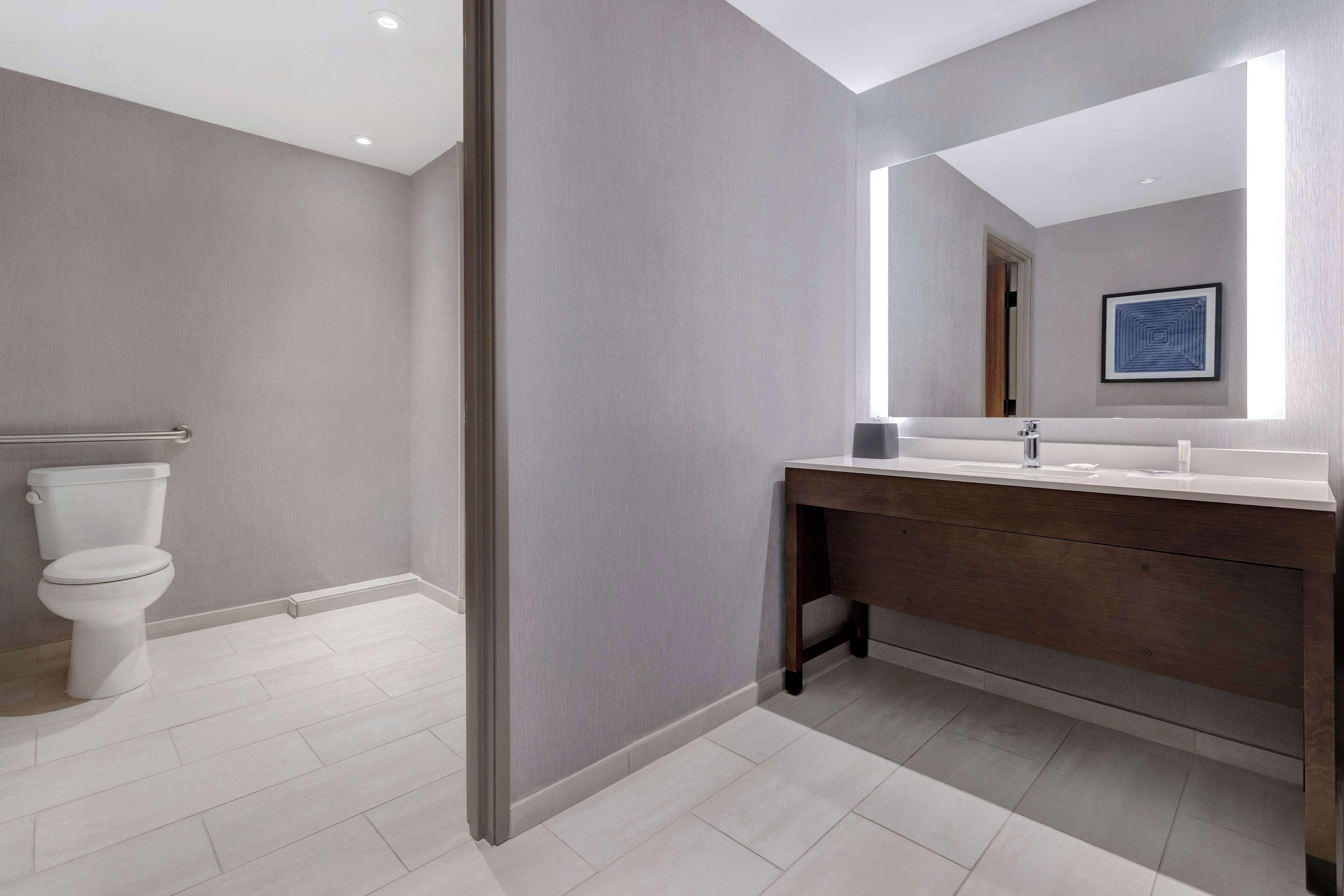 Un baño moderno con inodoro, tocador con espejo y piso en tonos claros.
