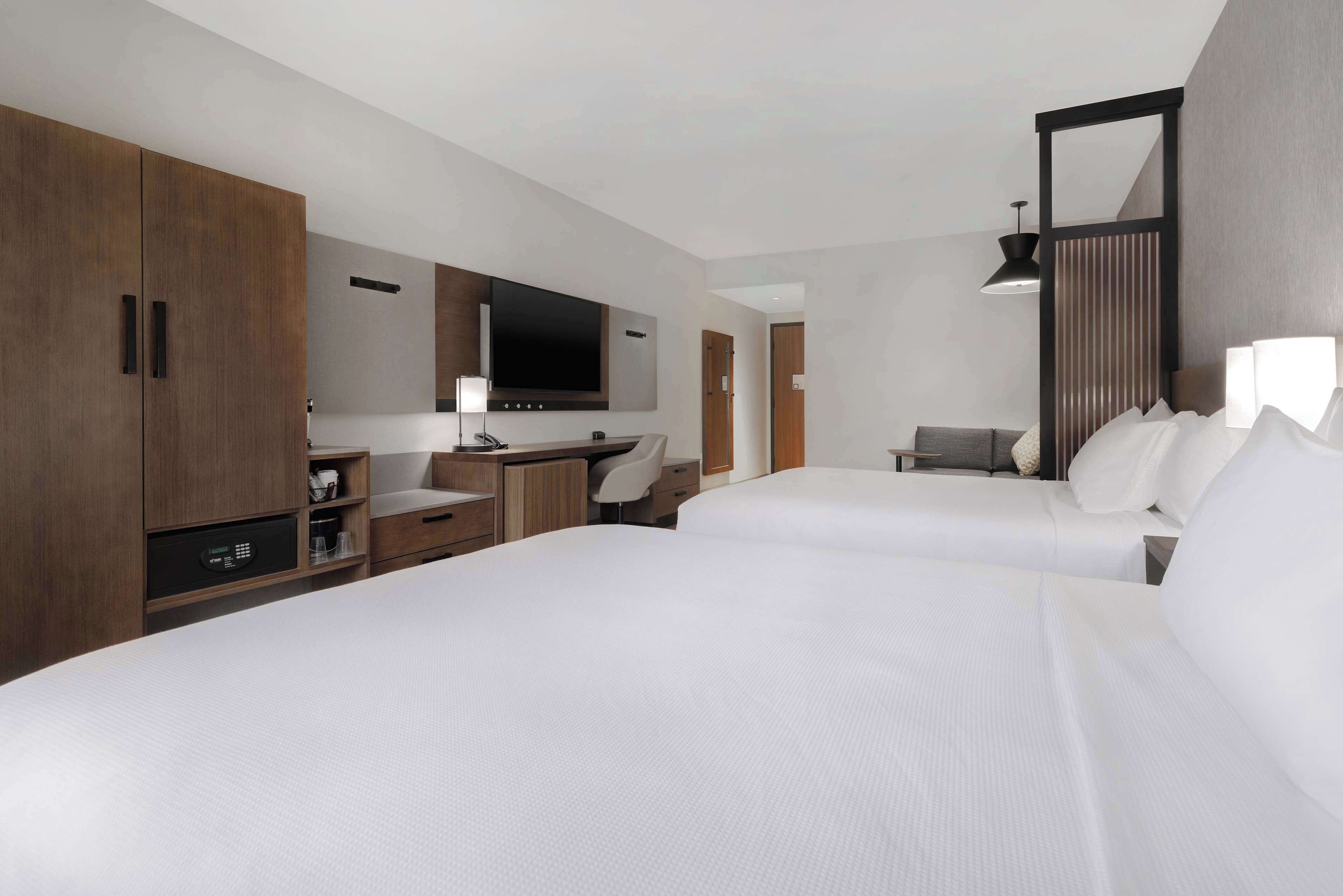 A hotel room with two beds, a desk, a TV, and a wardrobe.