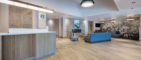 A modern reception area with a wooden reception desk, a blue seating area, and a large wall with a geometric pattern.