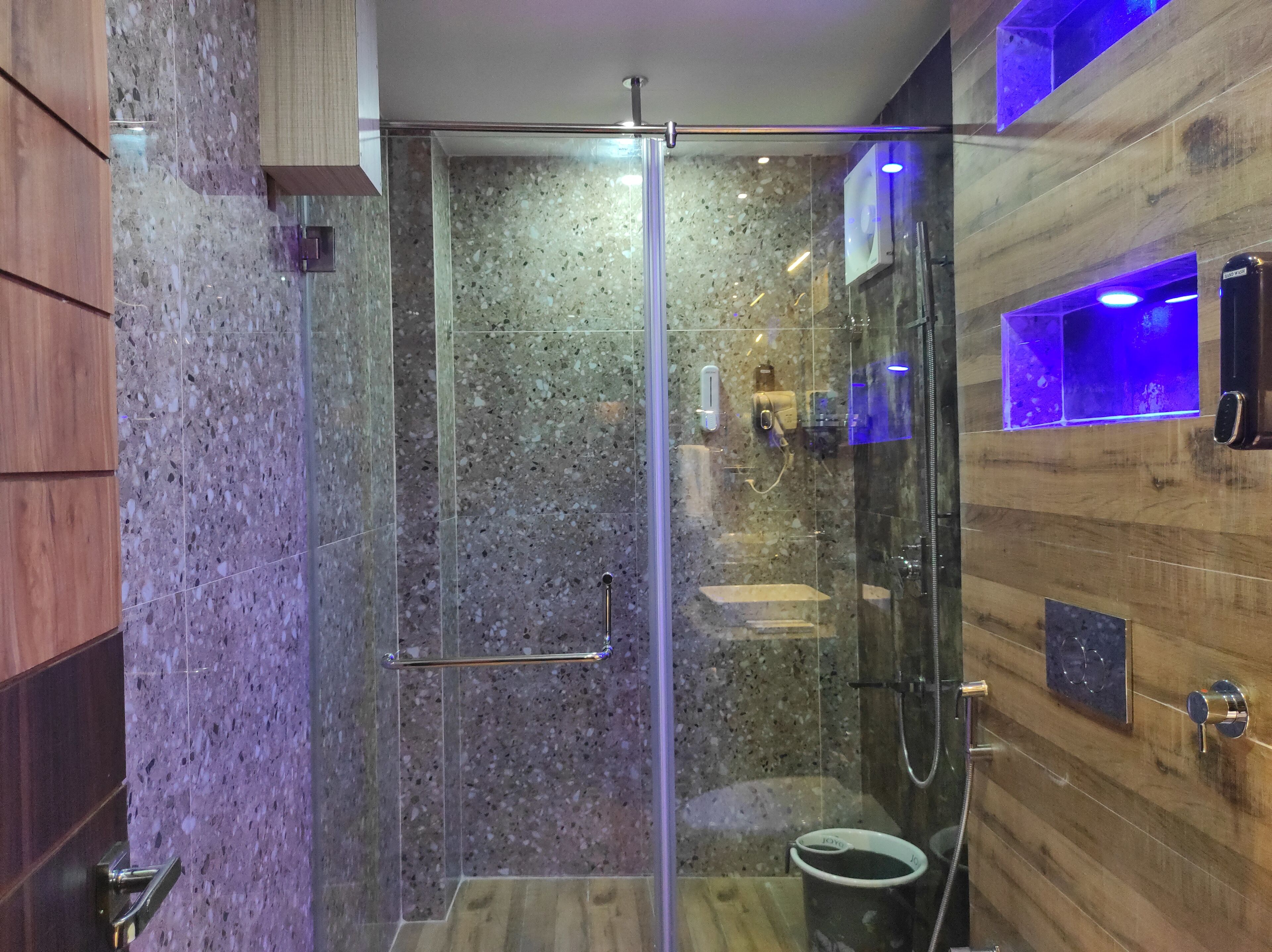 Un baño moderno con cabina de ducha de vidrio, paneles de madera y lavamanos empotrado.