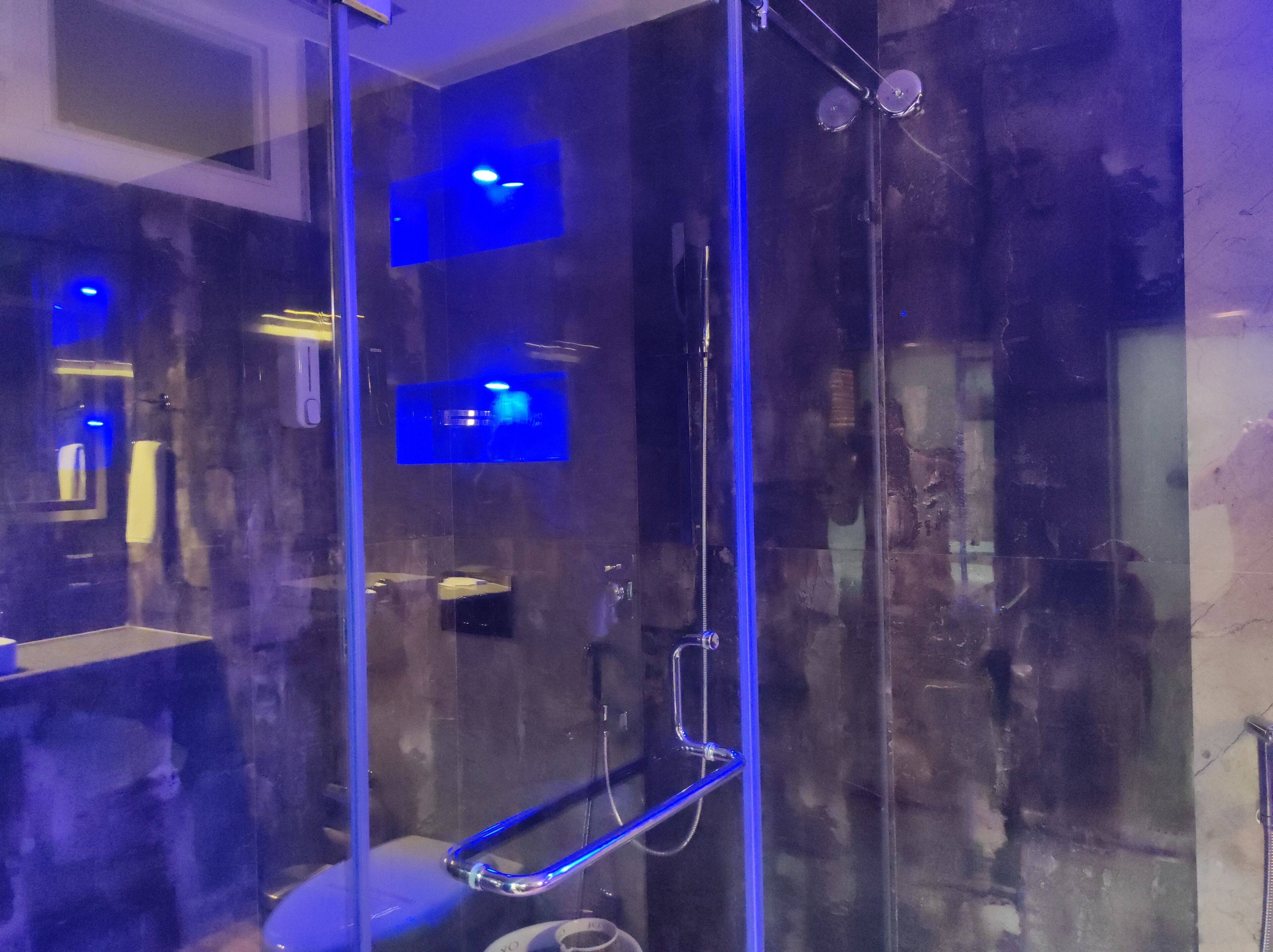 A modern bathroom with a glass-enclosed shower, a visible toilet, and a sink.
