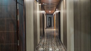 Un pasillo con piso estampado, paredes de madera y techo con vigas y luminarias a la vista.