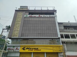 A building with a sign for 'Avas Inn Hotel & Restaurant' and a 'JKTYRE Steel Wheels' shop below.