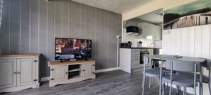 A compact living space with a television, kitchenette, and dining area.