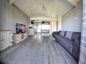A compact living space with a sofa, TV, kitchenette, and dining area.