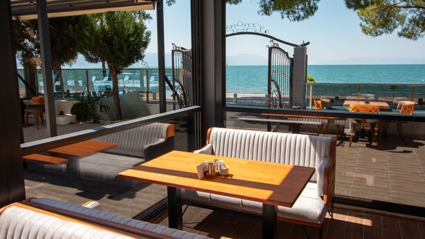 A terrace with seating and tables overlooking a body of water. - LAKE LİFE HOTEL (Iznik)