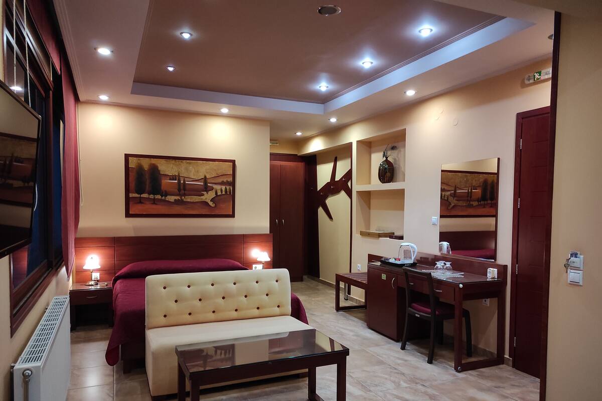 A hotel room with a bed, a sofa, a desk, and a dining table.