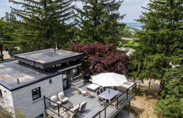 A modern house with a rooftop deck, outdoor seating, and a view of the ocean.