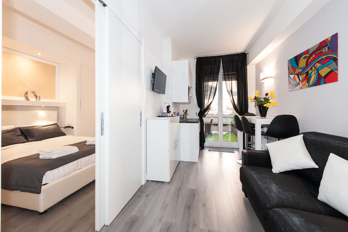 Ein modernes Hotelzimmer mit Bett, einer kleinen Küchenzeile, einem Sofa und einem Essbereich.