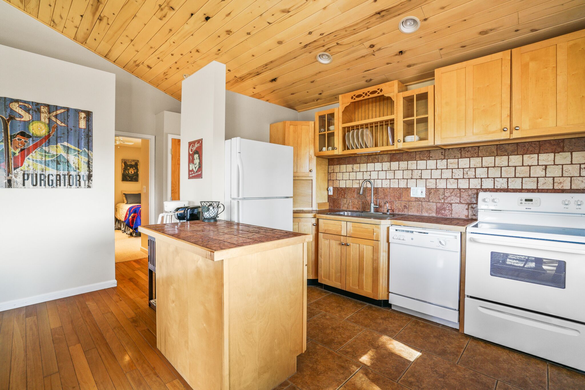 A kitchen with wooden cabinets, a central island, a dishwasher, and a stove.