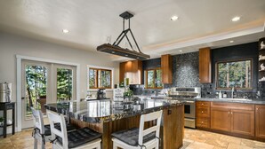 A modern kitchen with a central island, wooden cabinets, and a large window providing a view of the outdoors. - Luxury Home on 8 Acres - Fantastic Views and outdoor space - 20 Min to DGO (Durango)