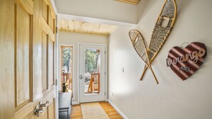 A hallway with wooden doors, a woven wall hanging, and a heart-shaped sign.