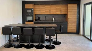 A modern kitchen with wooden cabinets, a central island, and bar stools. - Magnifique Maison Avec Jacuzzi (Marseille)