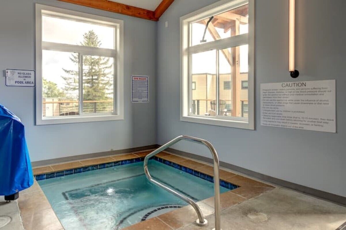 An indoor swimming pool with a metal ladder, a 'No Glass Allowed' sign, and a 'Caution' sign on the walls.