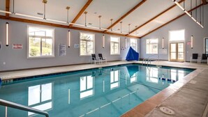 An indoor swimming pool with clear water, wooden beams on the ceiling, and windows allowing natural light. - Suite Spot at Sugar-Mountain Views (Sugar Mountain)