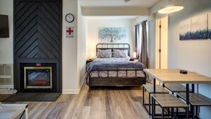 A bedroom with a bed, a fireplace, a table, and benches. - Suite Spot at Sugar-Mountain Views (Sugar Mountain)