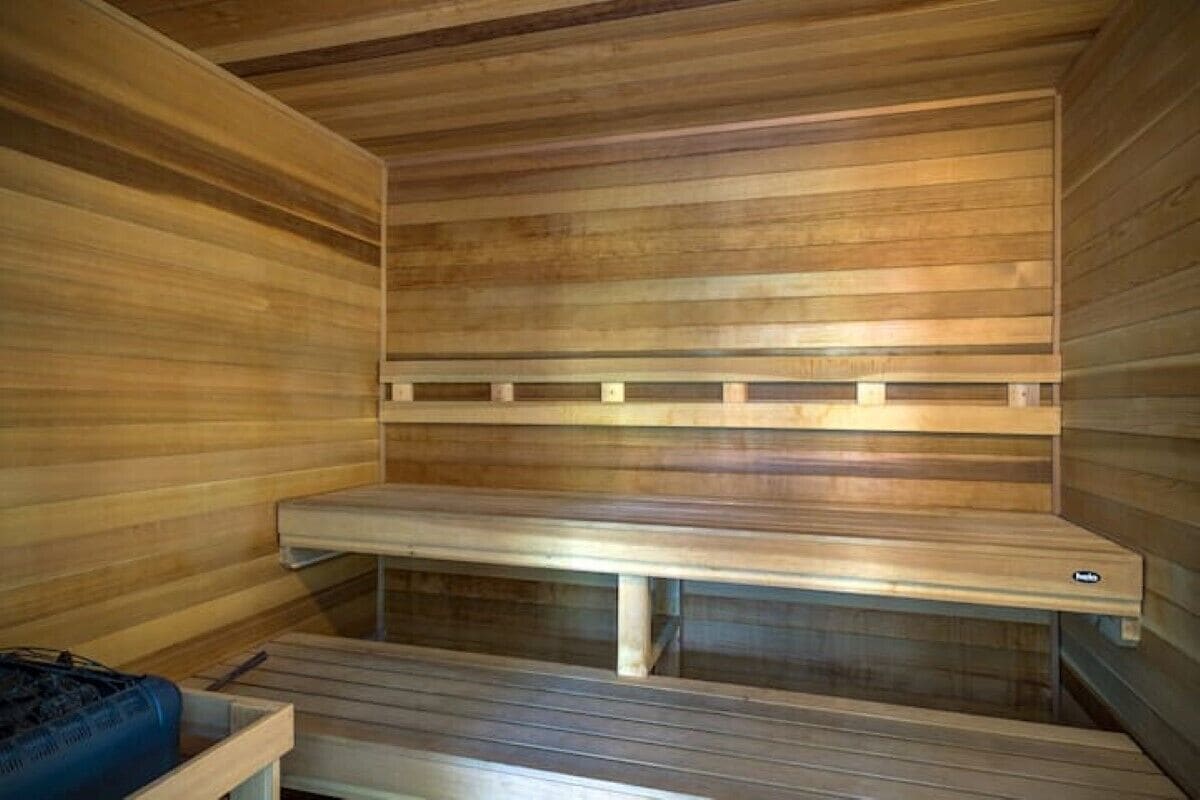 Una sauna con panche in legno e una panca con un pannello di controllo.