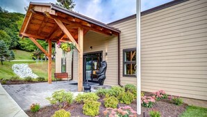 A house with a covered porch, a garden with various plants, and a statue. - Suite Spot at Sugar-Mountain Views (Sugar Mountain)