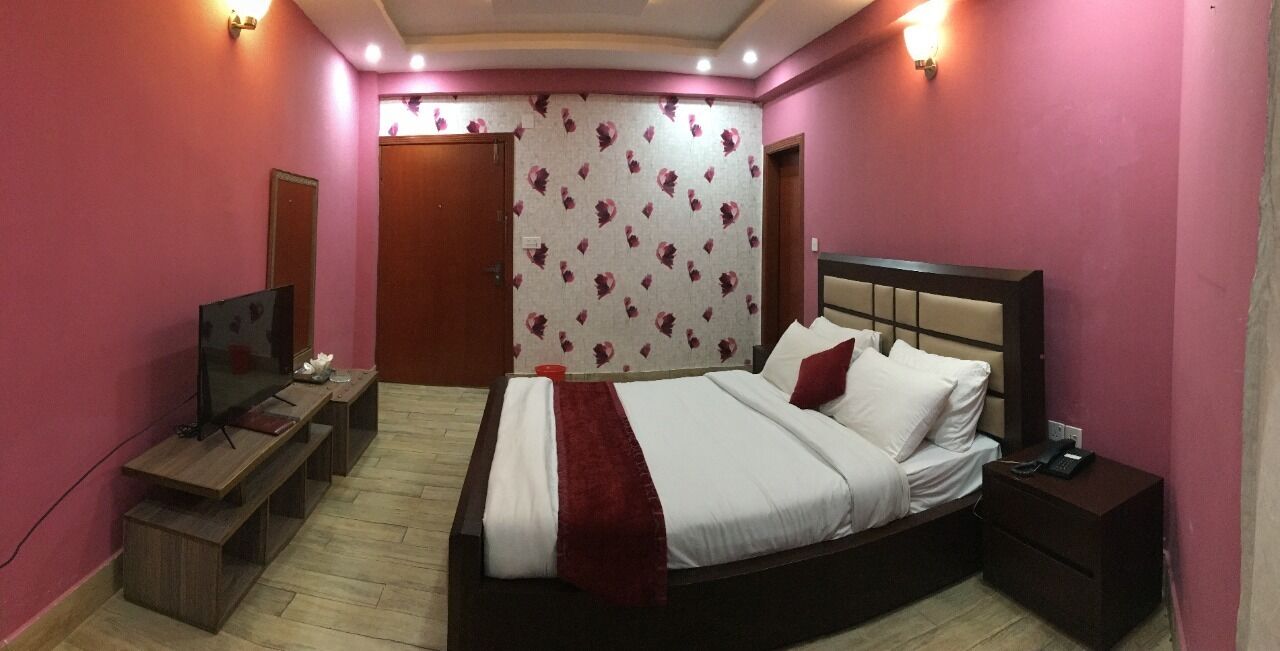 A bedroom with a large bed, bedside tables, a TV, and a wardrobe.