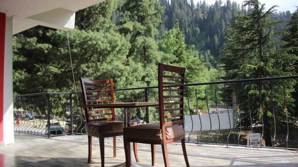 Two wooden chairs with metal frames on a balcony with a view of a forested mountain area. - Snow Crest Lodges (Mekhtar)