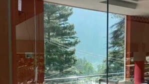 A room with a glass partition, a dining table with chairs, and a view of trees and a body of water. - Snow Crest Lodges (Mekhtar)