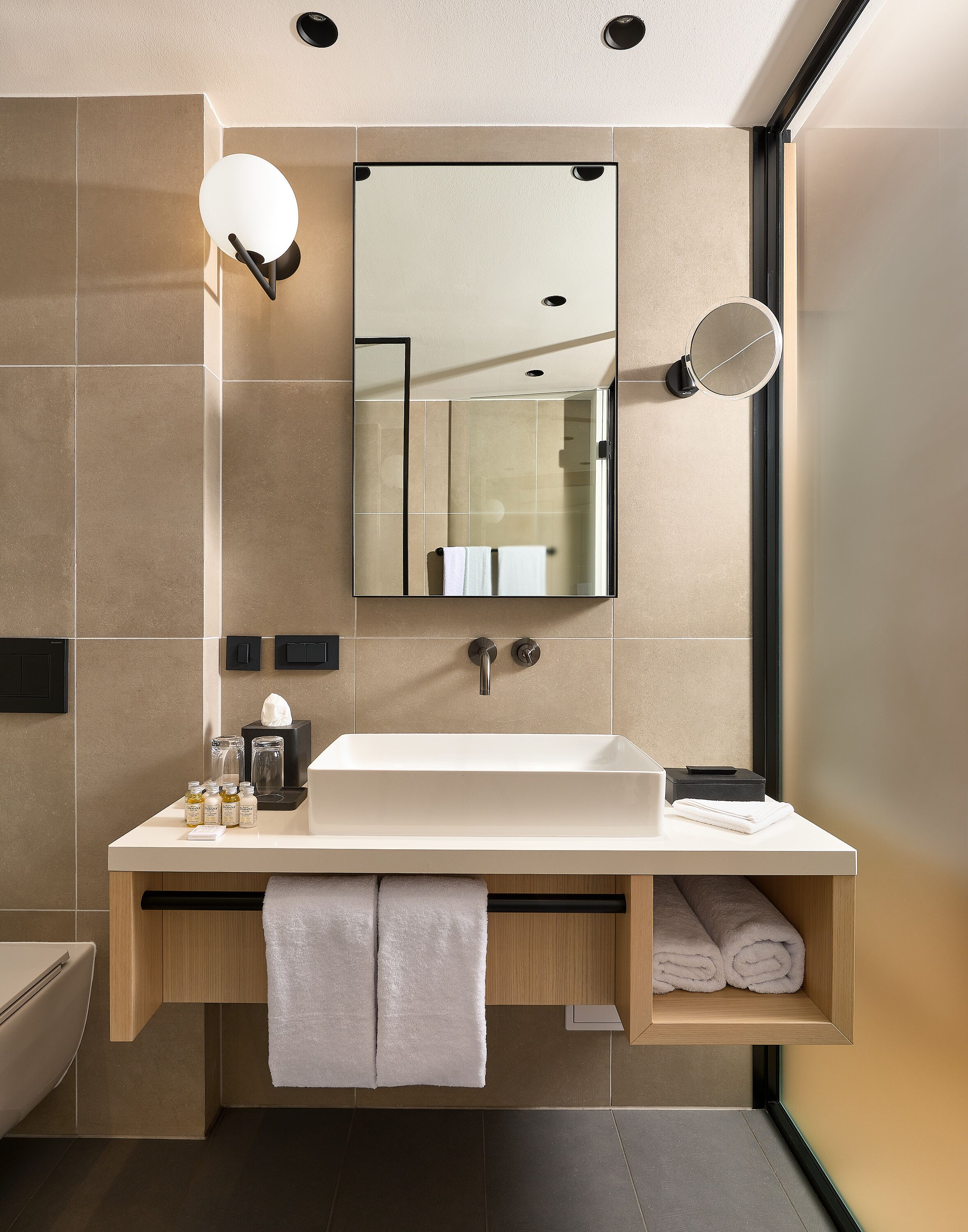 A modern bathroom with a large mirror, a sink, and a towel rack.