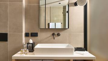 A modern bathroom with a large mirror, a sink, and a towel rack.