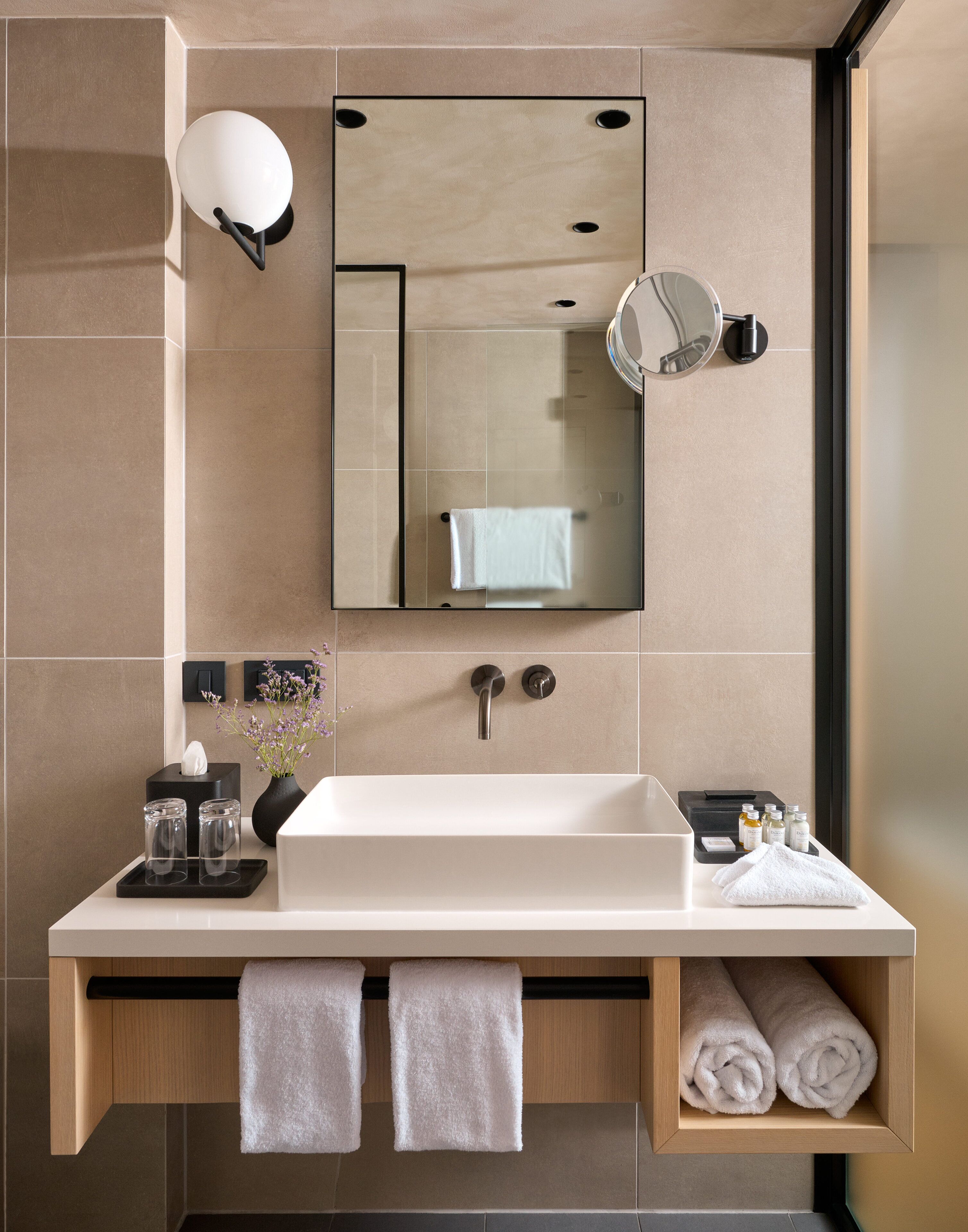 A modern bathroom with a large mirror, a white sink, and a towel rack.