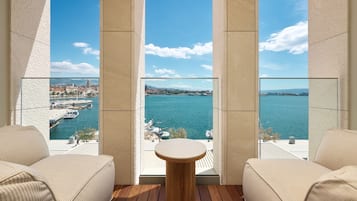 Enjoy a waterfront view from this balcony with a comfortable seating area featuring a round table and two sofas.