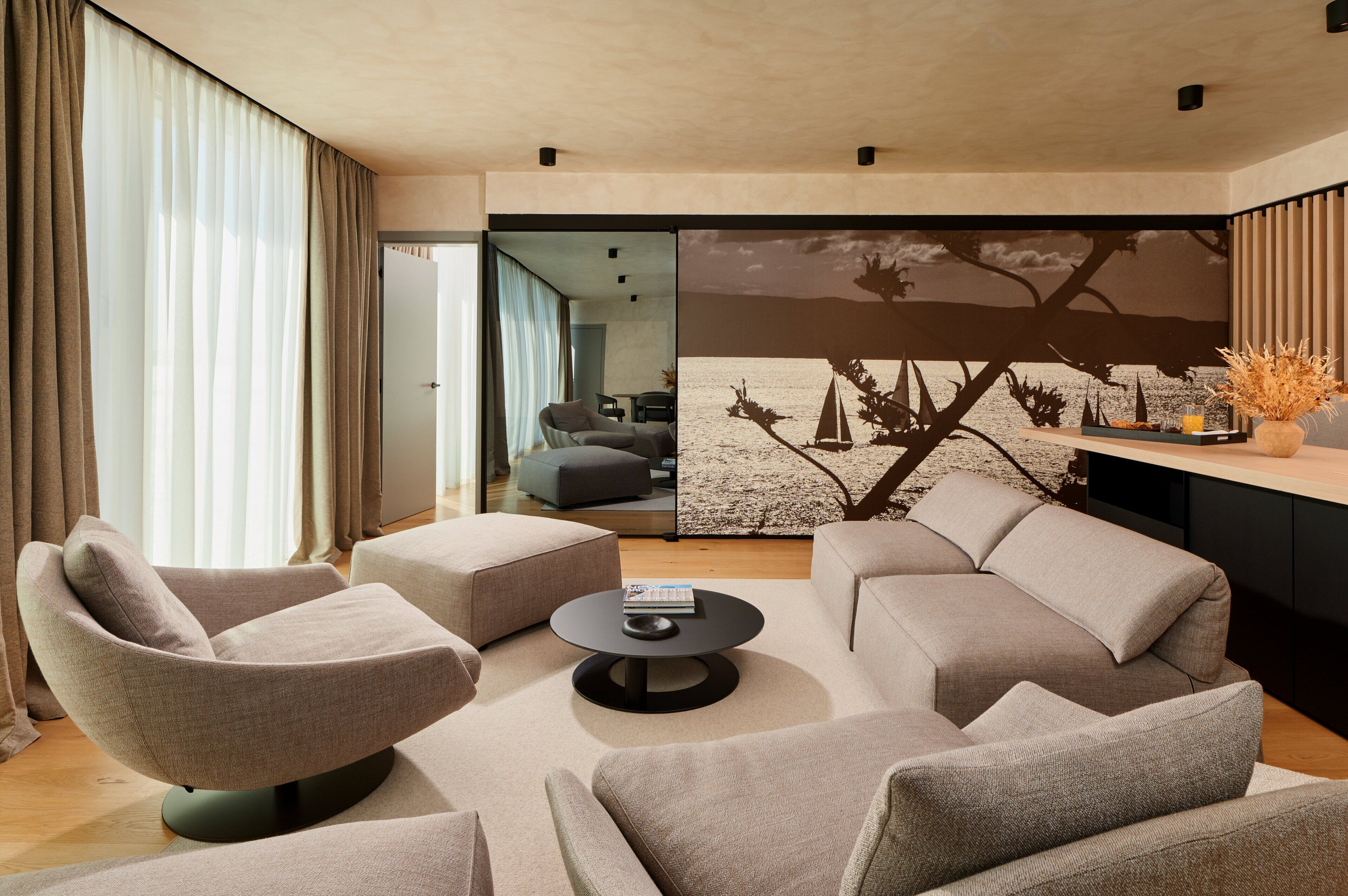 Una sala de estar moderna con un sofá modular, una mesa de centro redonda y un gran mural en la pared.