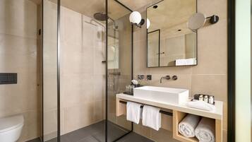 A modern bathroom with a glass-enclosed shower, a white sink, and a mirror.