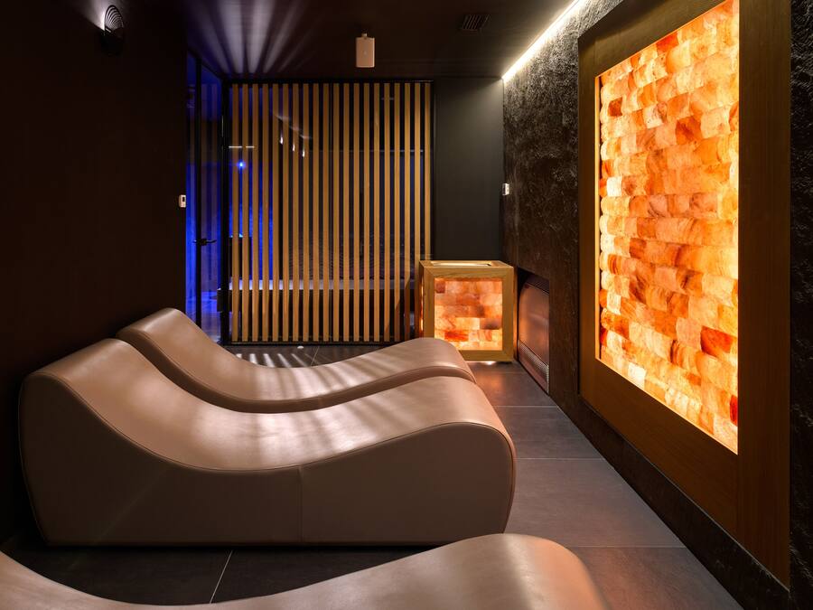Un espace spa moderne doté d’un mur en pierre chauffé, d’une table de massage et d’une cloison en bois.