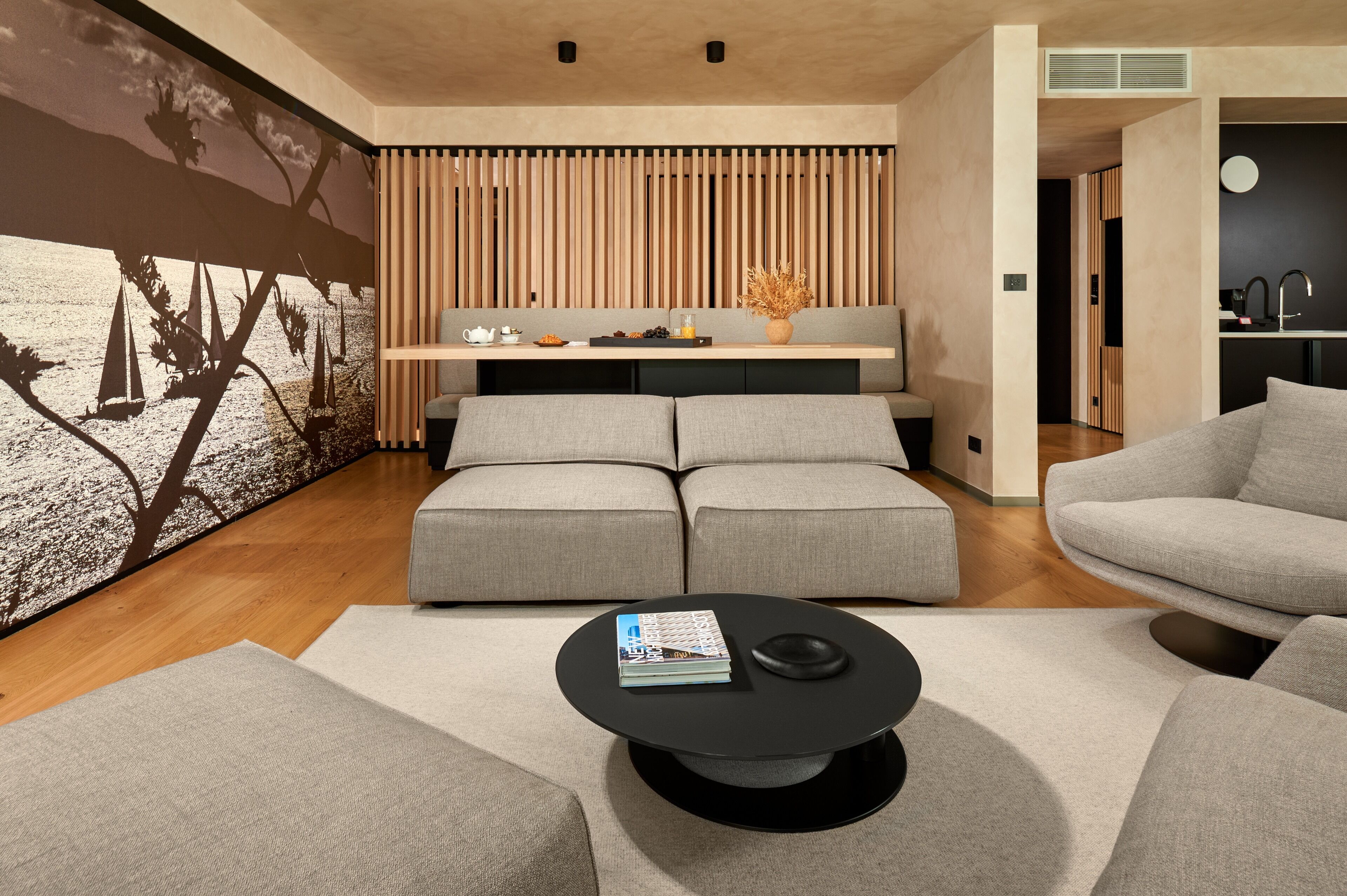 A modern living room with a sectional sofa, a coffee table, and a wall-mounted shelf with decorative items.