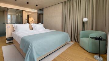 A modern hotel room with a large bed, a seating area, and a view through a glass door.