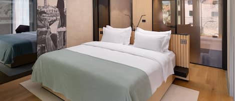 Ett modernt hotellrum med en stor säng, en mindre säng, ett stort fönster och utsikt över staden.