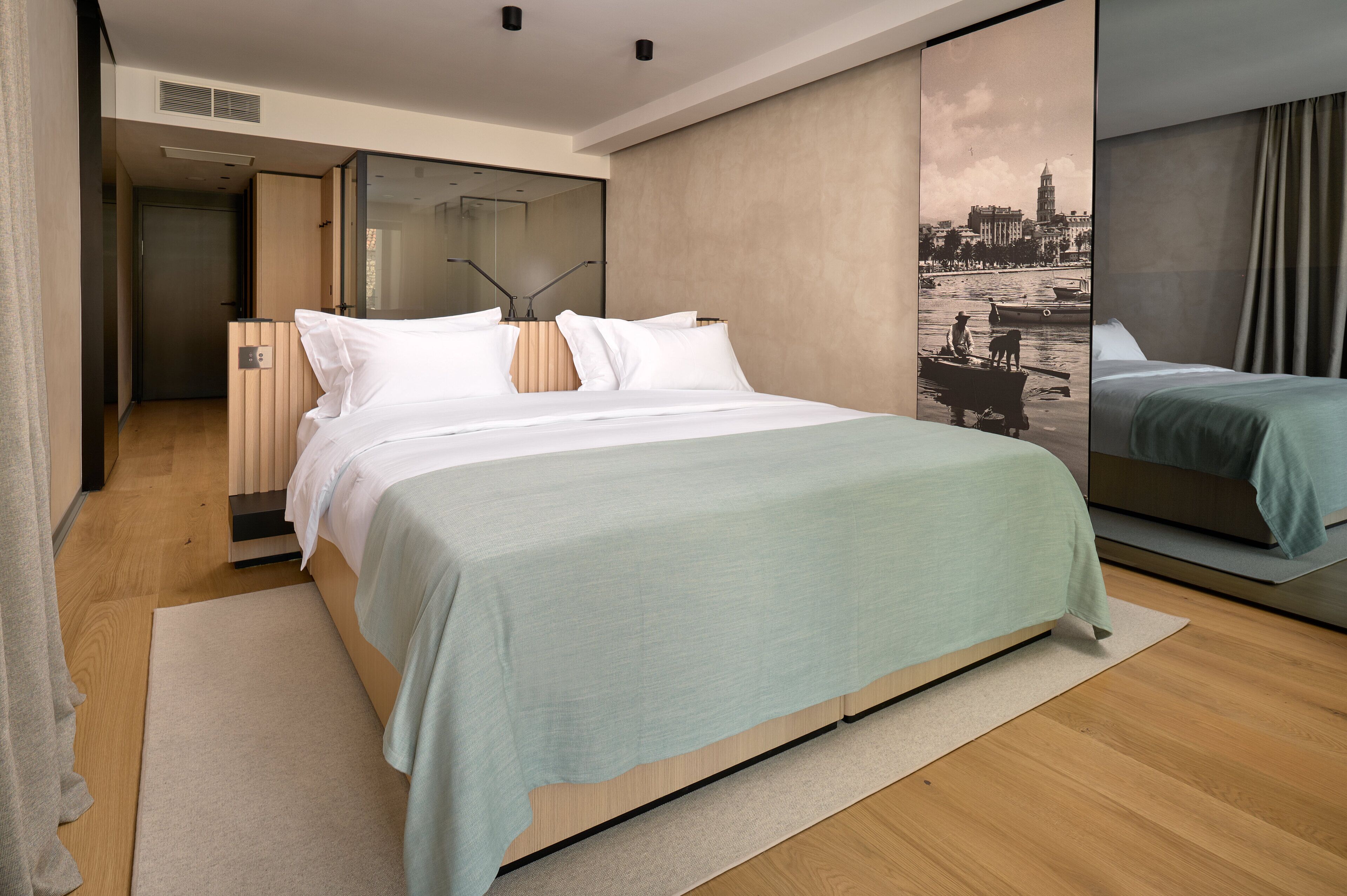 Una habitación de hotel moderna con una cama grande, vistas de la ciudad y una puerta corrediza que da a un baño.