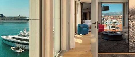 A modern hotel room with a balcony overlooking a marina and cityscape.