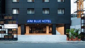 Exterior del Hotel Ark Blue con fachada moderna, una entrada destacada y plantas en macetas a la entrada.