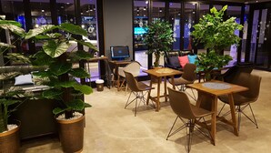 Un área de estar interior moderna con una mesa de centro, sillas y plantas en macetas.