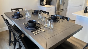 A modern dining area with a long table set for six, black bowls, clear glasses, and cutlery. - Near Zion NP I Dark Skies I Garage & Trailer Parking (Kanab)