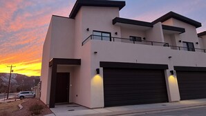 A modern two-story building with a flat roof, large garage doors, and a balcony on the upper floor. - Near Zion NP I Dark Skies I Garage & Trailer Parking (Kanab)