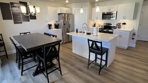 A modern kitchen with white cabinetry, stainless steel appliances, and a central island with bar stools. - Near Zion NP I Dark Skies I Garage & Trailer Parking (Kanab)