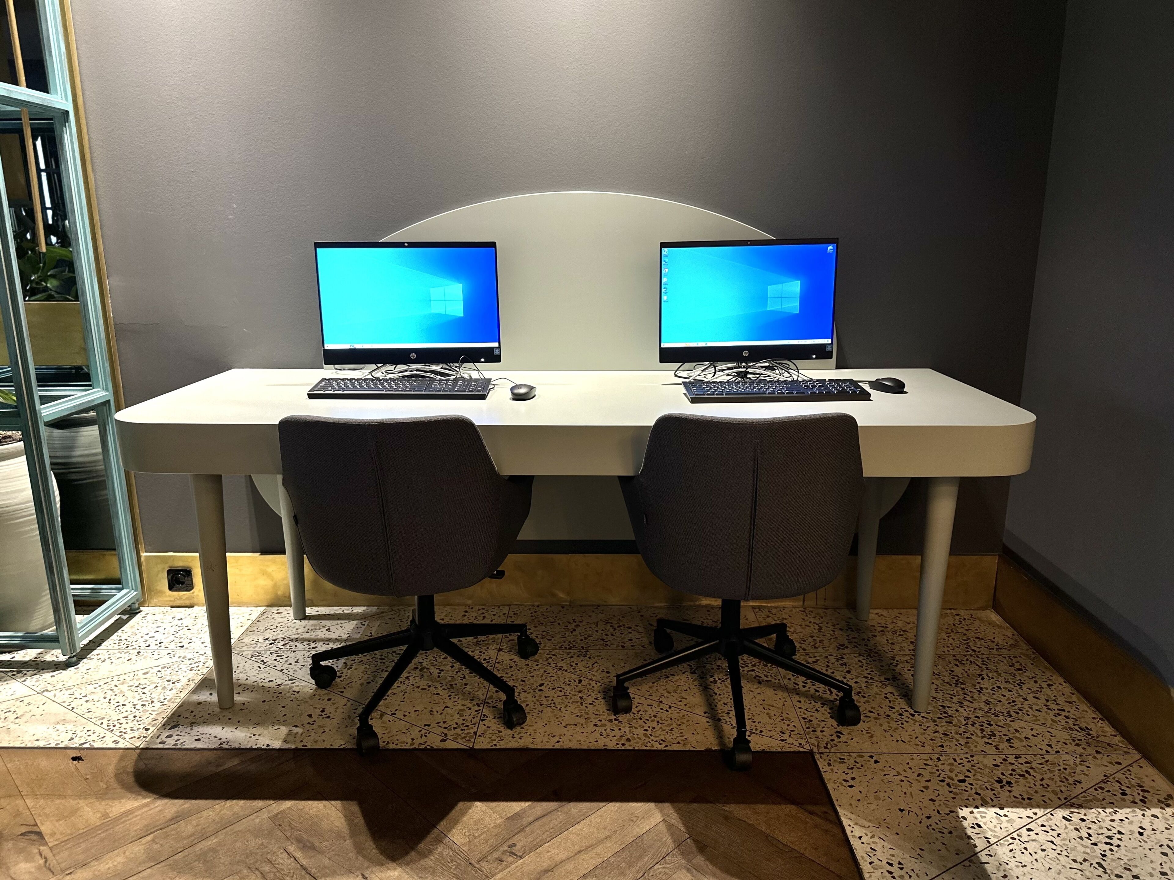 A workspace with two HP desktop computers, two office chairs, and a white desk.