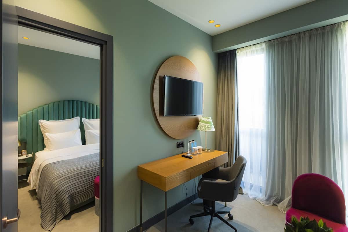 Une chambre d’hôtel équipée d’un lit, d’un bureau, d’une chaise, d’une télévision et de rideaux.