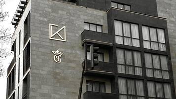 Un edificio moderno con un logotipo destacado en la fachada, varios balcones y ventanas grandes.